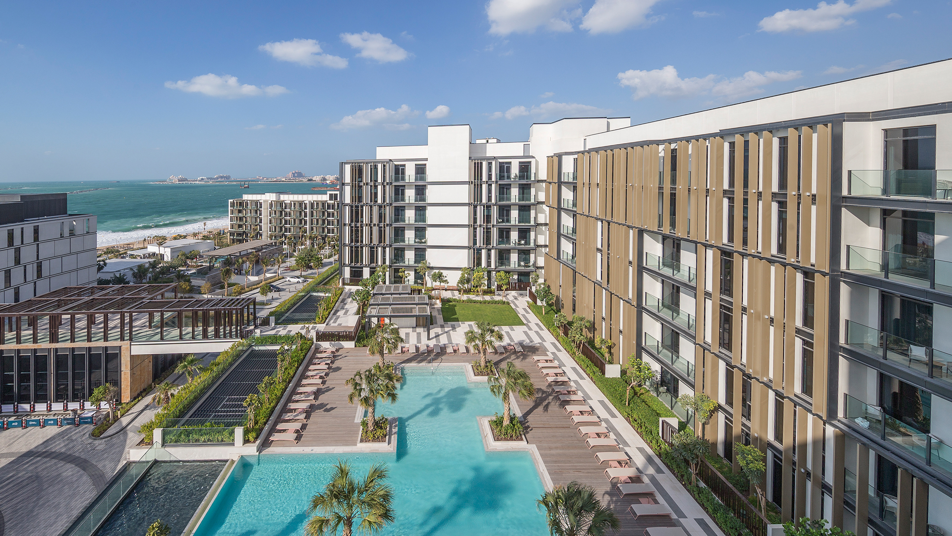 Banyan Tree Dubai resort pool at bluewaters island with sun loungers, surrounded by modern buildings, near the sea.